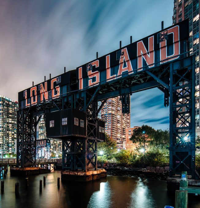 The Long Island sign illuminated at night, overlooking the water